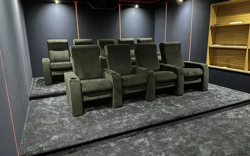Two rows of green velvet cinema recliners on a raised tier