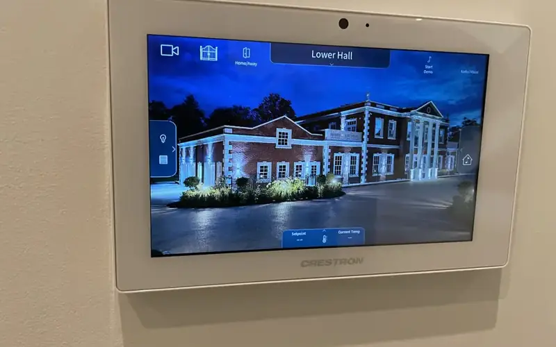 Crestron touch panel on a wall showing a home control screen