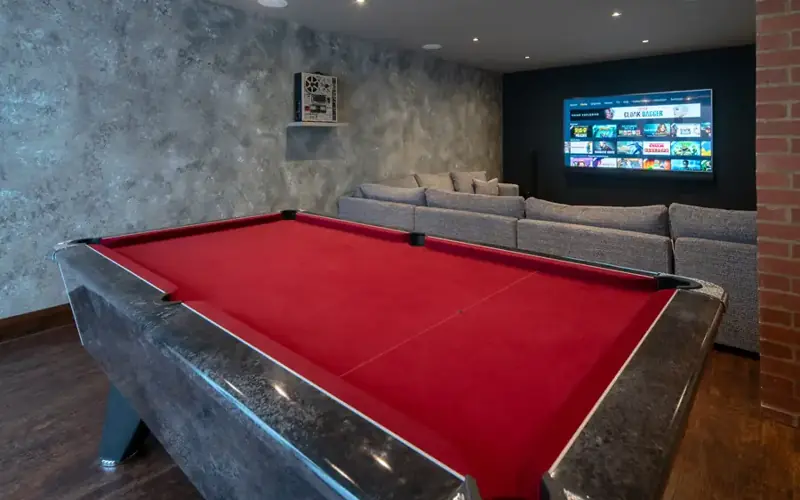 Games room with a wall mounted TV behind a red pool table