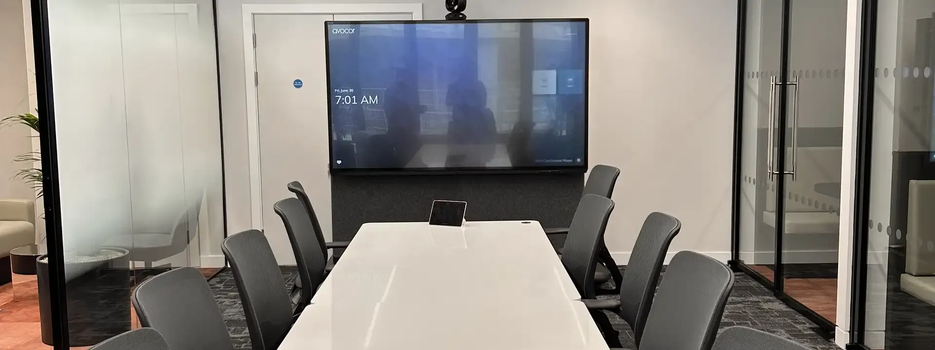 Contact Cork AV: glass walled meeting room with a video call screen and camera at the end of the table