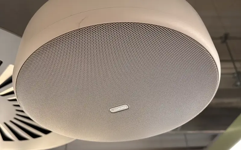 Close view of a white pendant speaker hanging from a ceiling