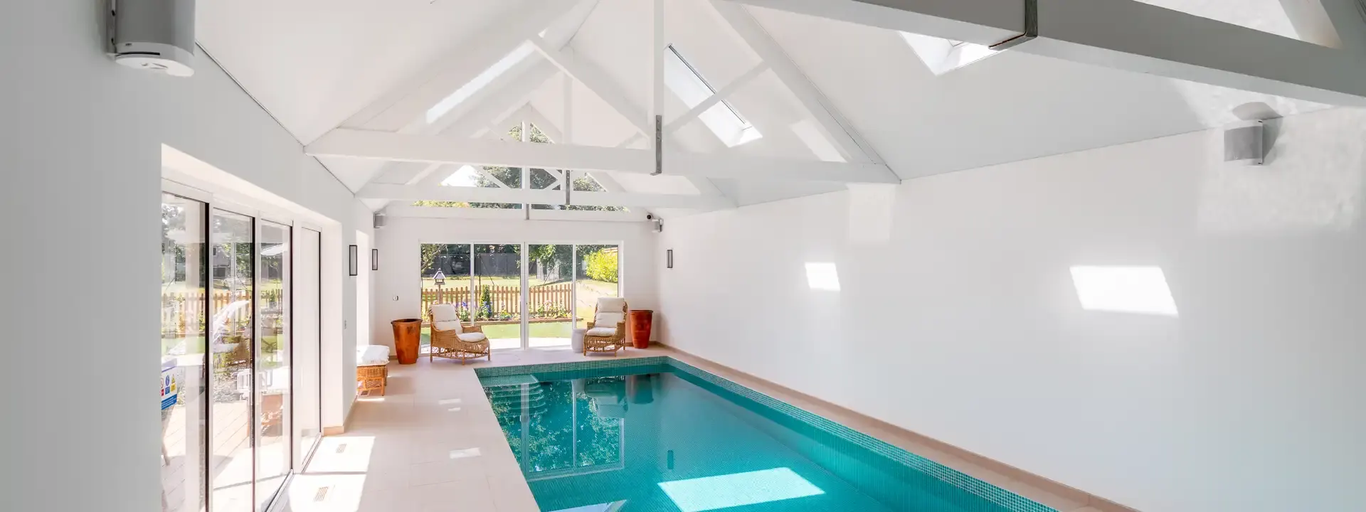 AV installation example: bright indoor pool house with white speakers mounted high on the walls