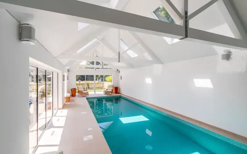 Bright indoor pool house with white speakers mounted high on the walls