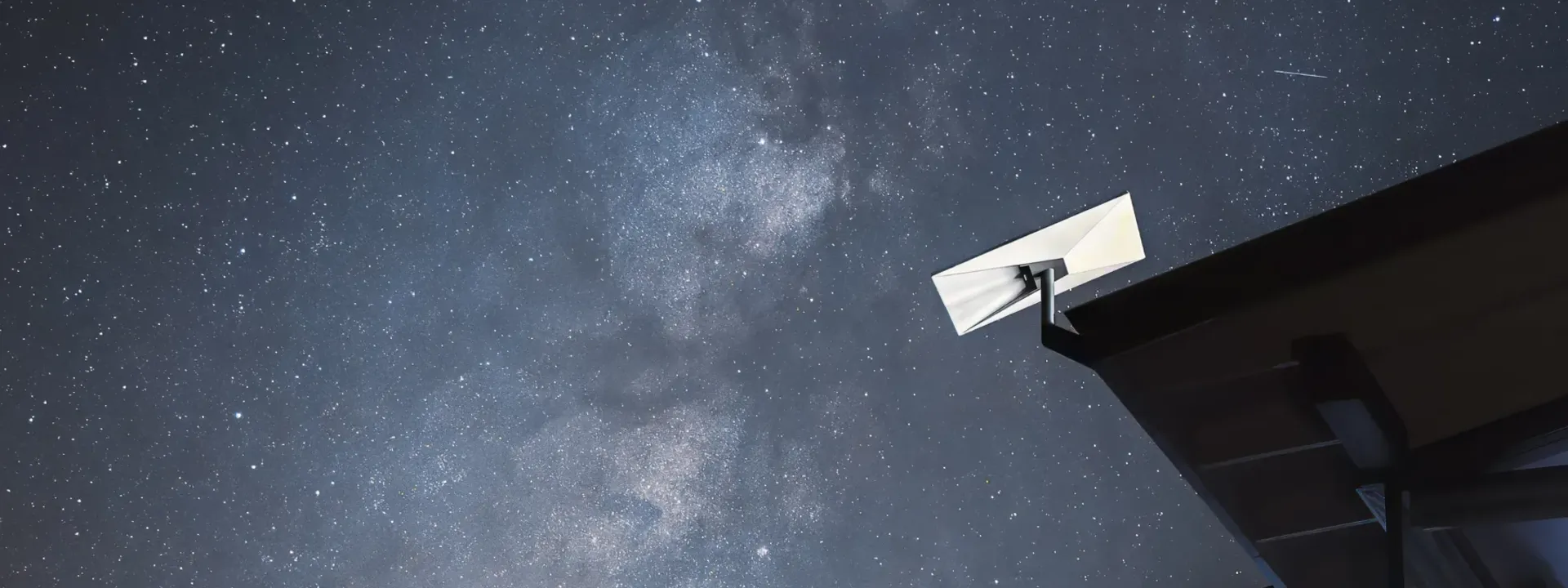 Starlink installation: a Starlink dish fixed to the eave of a timber roof under a clear starry sky